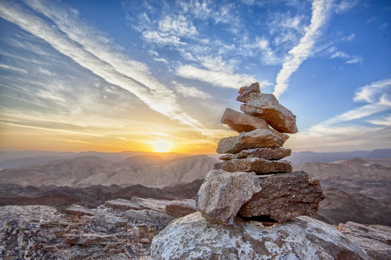 Rocks balancing on a cliff, sun rising in background